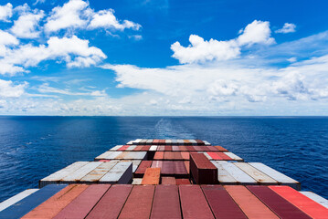 View on the containers loaded on deck of the large cargo ship. She is sailing through calm, blue...