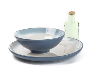 a blue soup bowl on a blue dinner plate with a bottle for olive oil isolated on white