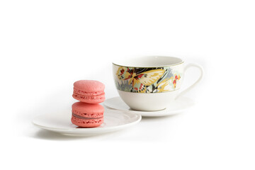 a pink macaroon cookies with a colorful teacup on a white background