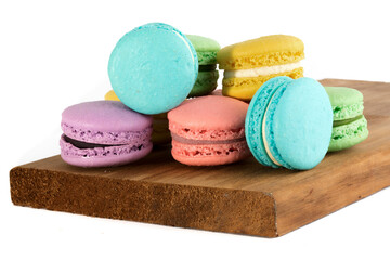 closeup of colorful macaroon or meringue cookies on a wooden board on a white background