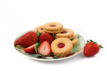 a plate of strawberry cream cookies and strawberries on a white background