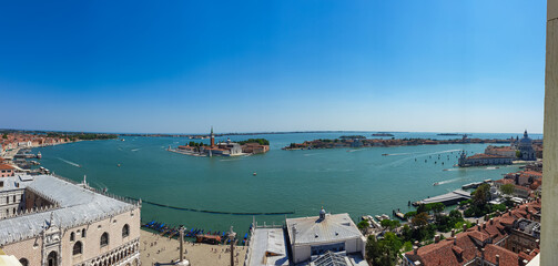 Aerial view from St Mark bell tower Campanile of the old town of Venice, Veneto, Italy, Europe. Looking at Piazza San Marco and the Venetian Lagoon. UNESCO World Heritage Site. Urban tourism in summer - obrazy, fototapety, plakaty