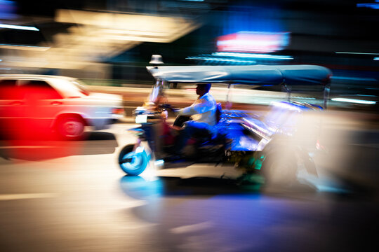 A tuk-tuk zooms through the night.