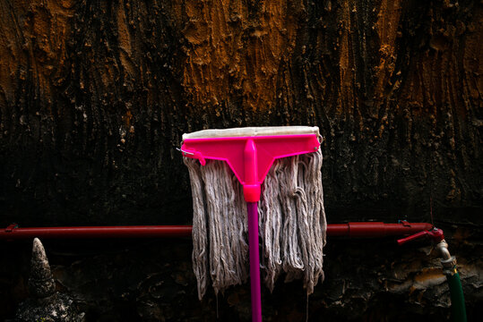 A old mop against a wall.