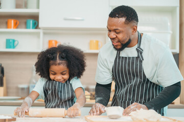 In a home kitchen, black father and his daughter bond over cooking a meal food, their laughter and love filling the air, embodying the joy of African American family life, Father's Day concept