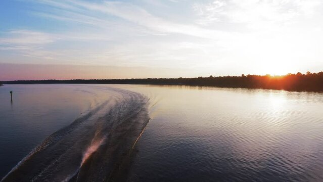 Aerial: Drone Backward Shot Of Wake Pattern In Tranquil River Stream Under Cloudy Sky At Sunset - Jefferson County, Texas