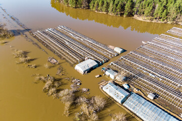 Agricultural farm fields with greenhouses flooded during a strong spring flood, river flood in the...