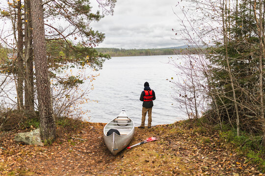 Young man standing by kayak in wilderness adventure