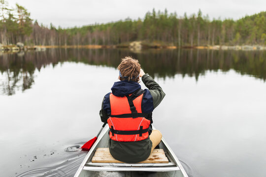 Young man rowing a kayak on a forest Lake