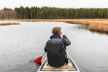 Young man rowing a kayak on a forest Lake