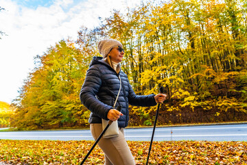 Mid-adult woman exercising nordic walking in city park
