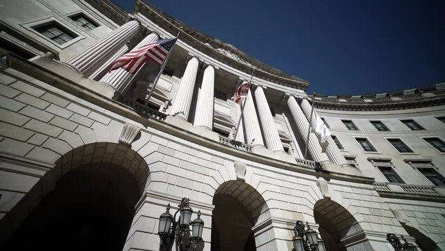 Turning wide angle view looking straight up at the flags and columns of the US Environmental Protection Agency, EPA building in Washington, DC.