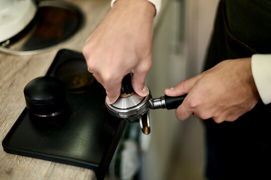 barista tamping coffee in a coffee cone