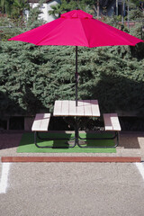 Picnic table and red umbrella set up on a parking lot