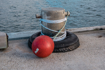 Photograph of white rope wrapped around a steel boat bollard with a red mooring buoy on King Island...