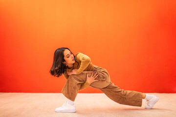 young generation z woman dancing in front of an orange background