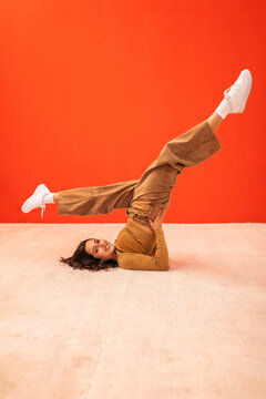 young generation z woman dancing in front of an orange background