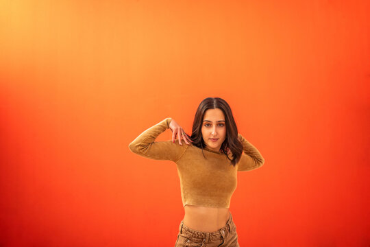 young generation z woman dancing in front of an orange background