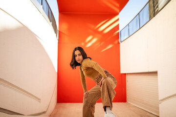 young generation z woman dancing in front of an orange background