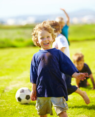 Obraz premium Dirt, smile and portrait of child for soccer by grass, lawn and outdoor playing with happiness in nature. Boy, freedom or fun in football for activity, comic and excited in youth outside with friends