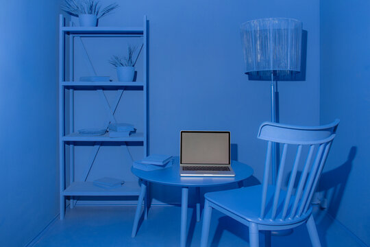 A mockup with a laptop in an entirely monochrome blue room in 3d style