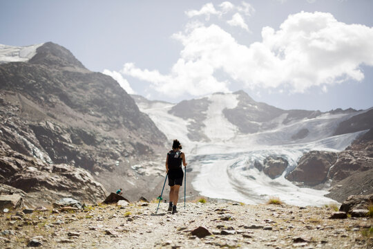 trekker girl on snowy mountain walking to the glacier.