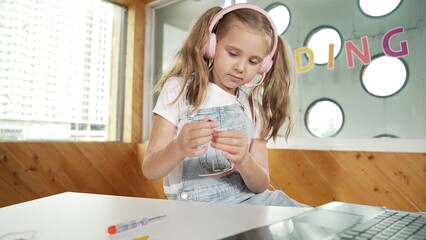 Pretty girl wearing headphone while study electronic equipment. Caucasian child doing science...