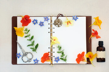 Natural alternative herbal medicine for colds and flu remedy with borage, nasturtium and lemon balm herbs and flowers with old leather notebook. On hemp paper background.