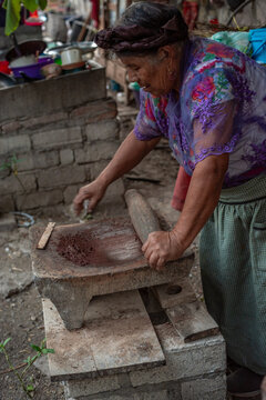 Senior woman rolling a stone pin to make chocolate