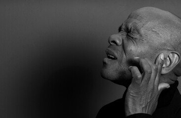 deaf man suffering from deafness and hearing loss on grey black background with people stock image...