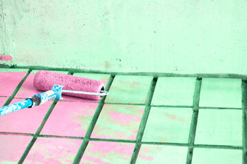 Roller painting green wall surface with pink paint