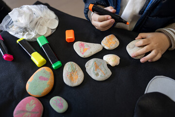 Children's hands drawing animals on flat stones. Drawing with colored felt-tip pens.