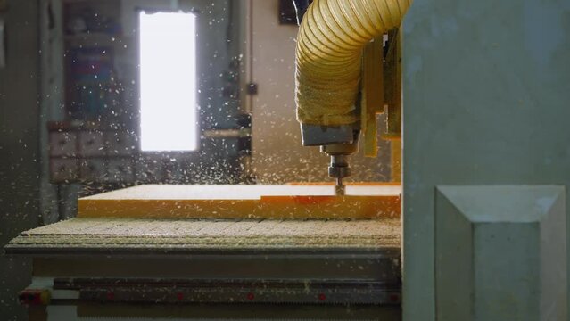 CNC machine in action with particle spray and bright window in background