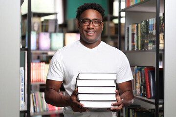 Heavy stack of new books and textbooks in hands of african american female student in modern...