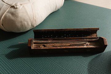 Closeup shot of an incense bar and meditation cushion, preparation for yoga relaxation ritual practice at home. 