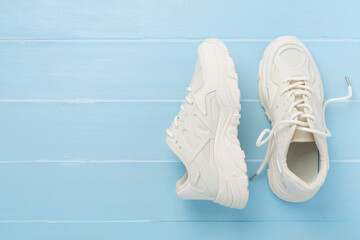 White woman trendy sneakers on wooden background, top view
