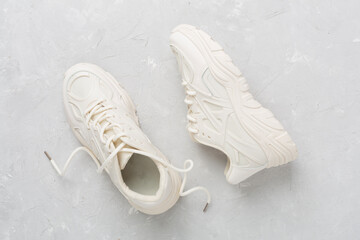 White woman trendy sneakers on concrete background, top view