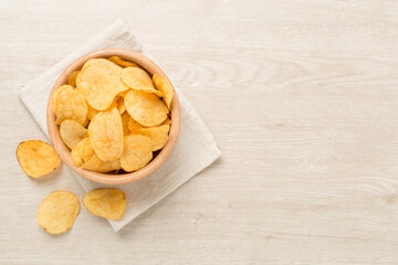 Appetizing potato chips on wooden background, top view