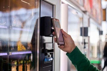 A man paying with his mobile phone at a vending machine.