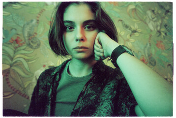 Portrait hipster girl makes eye contact with camera in green light