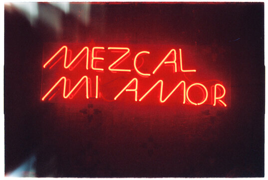Red neon frase in spanish language on bar wall: mezcal mi amor 