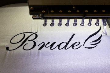 Inscription bride with black thread. Wedding day preparation. Elegant bridal lingerie. White accessories for the bride. Close up