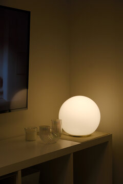 Round table lamp lights up in the night on the shelf