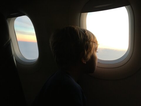 A Kid Looking Out of an Airplane Window