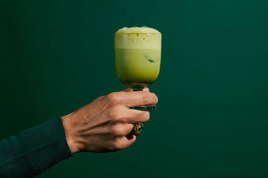 holds a glass with iced matcha latte