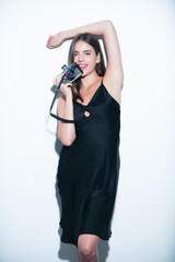 Portrait of pretty young woman with photo camera of photographer. Portrait of a sensual girl with a camera in hand on a white background. Isolated studio.