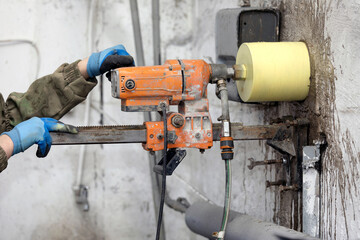 Worker using an electric drill to make a hole in a concrete wall, closeup - 789647198