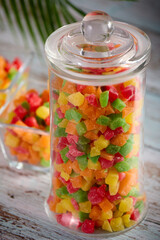 Healthy sweet snack of candied fruits in a glass dish on a wooden table. Close-up transparent glass jar and bowls are filled with colorful delicious candied fruits. 