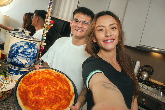 Man and woman smiling with a pizza