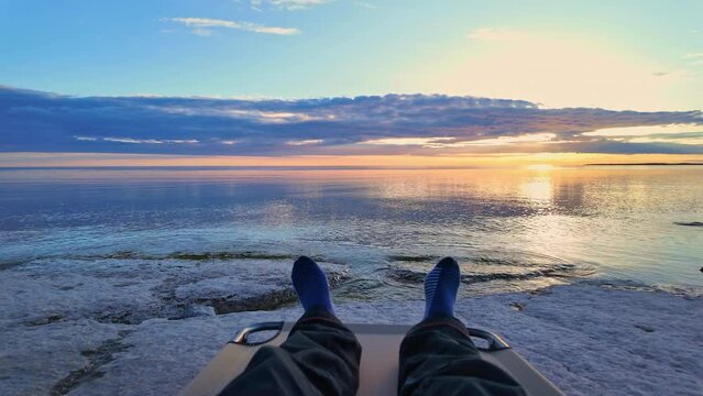 Traveler resting and relaxing at Lake Ontario Prince Edward County coast after long day. Epic sunset picturesque destination view at limestone shores and beach. Clear waters stunning view sun set.